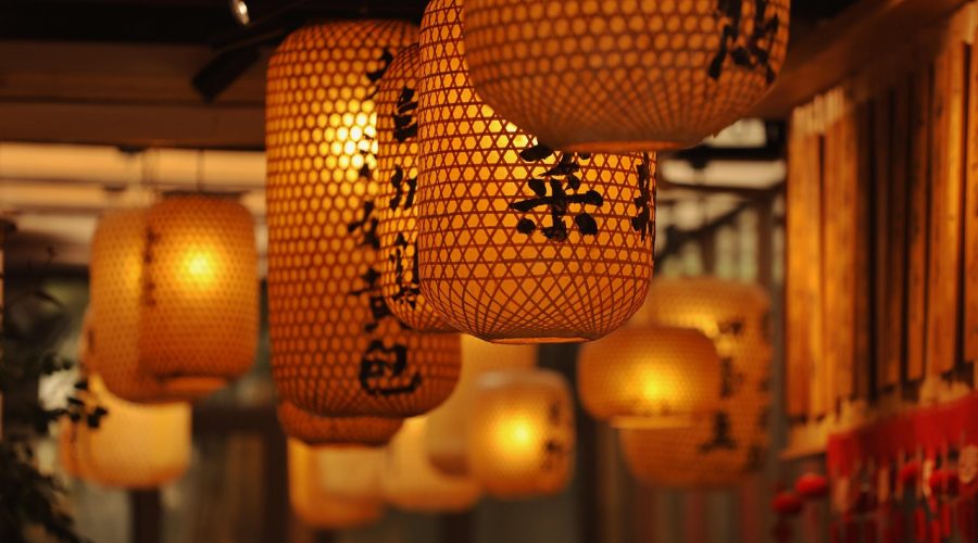 节日夜晚城市街道悬挂红灯笼，人群在灯下走过，暖色灯光映出节日氛围，画面热闹